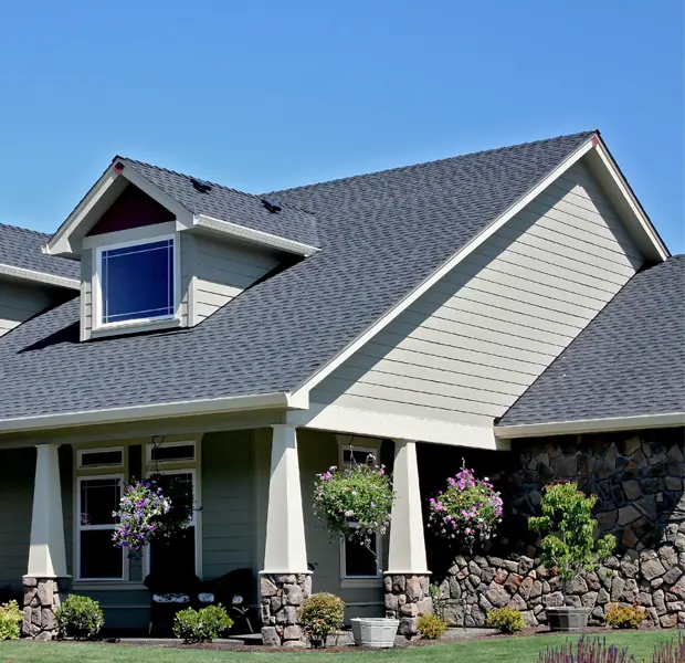 A beautiful residential home with a newly installed dark asphalt shingle roof by Elliott Roofing in Middle Georgia. The well-structured roof design complements the beige siding and stone accents, creating a polished and durable exterior. With dormer windows and a spacious front porch adorned with hanging flower baskets, this home highlights both aesthetic appeal and structural integrity. Elliott Roofing's commitment to quality craftsmanship ensures long-lasting protection and enhances the beauty of homes in the community.